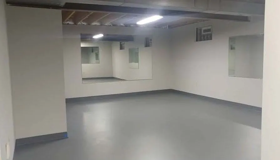 Finished basement with a mirrored wall and a poured floor