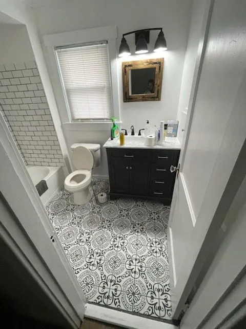 Dark vanity above an encaustic tile floor in a small bathroom