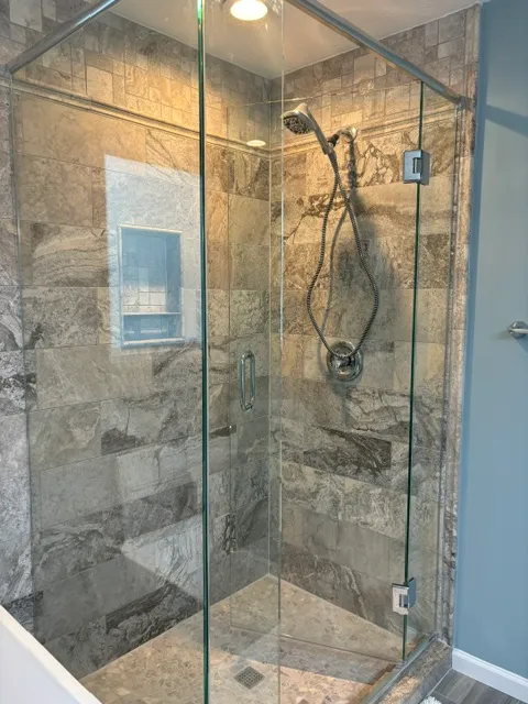 Veined marble shower behind frameless glass