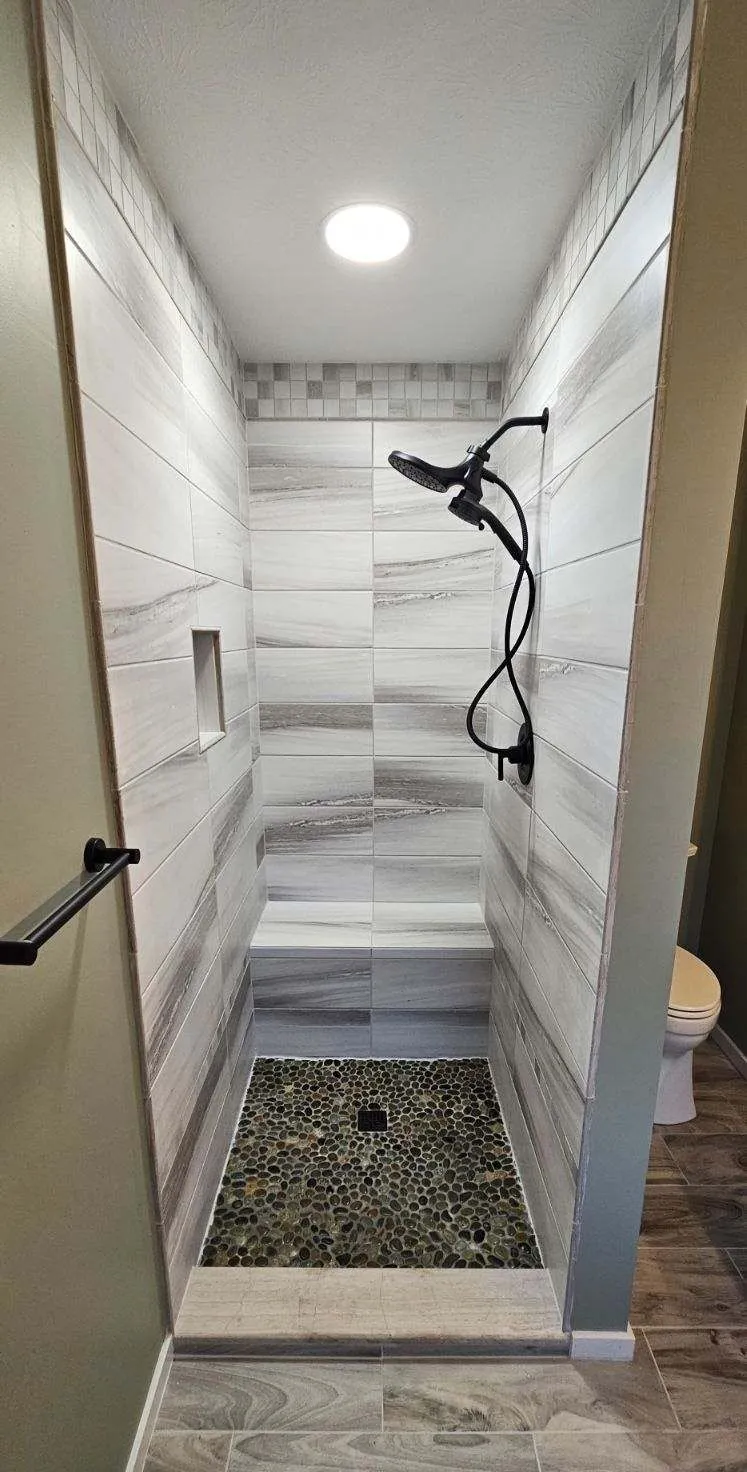Marble-veined shower wall running full height behind a built-in bench