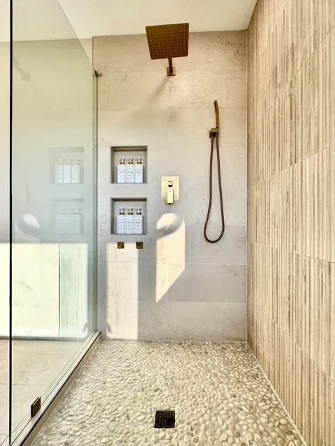 Tiled shower with two brass-trimmed niches