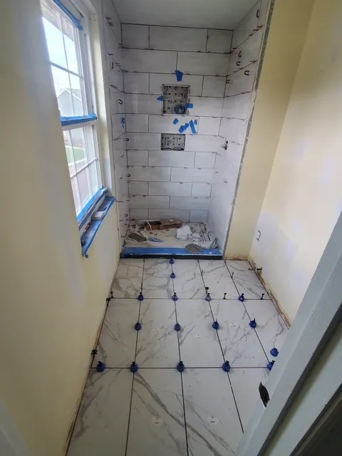 Shower pan being tiled, levelling clips in place