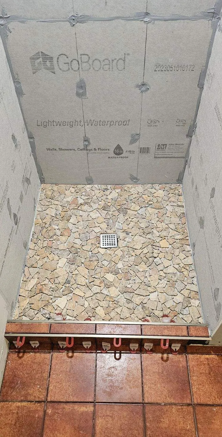 Shower pan waterproofed and sloped to the drain before tiling