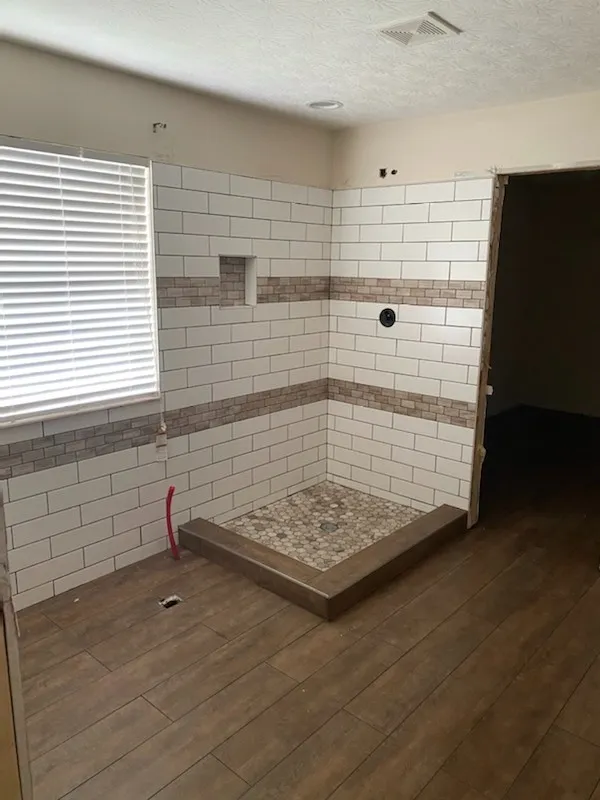 Subway tile shower part-tiled, pan set and walls going up