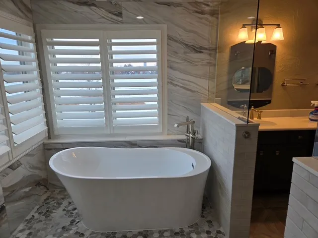 Freestanding tub beneath plantation shutters