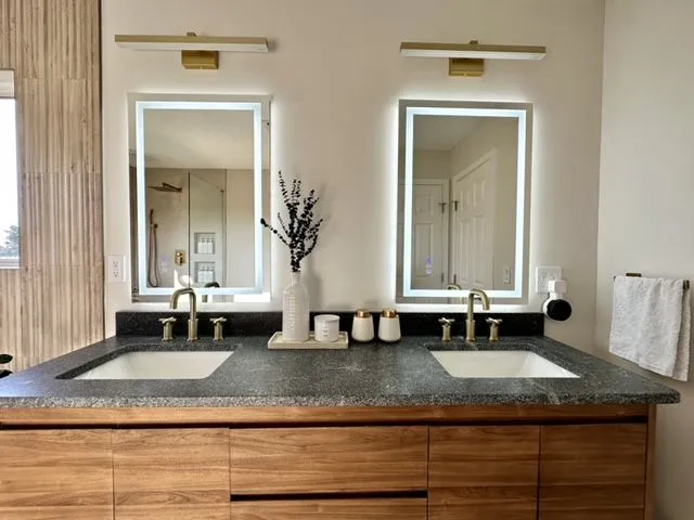 Walnut double vanity with twin backlit mirrors and a dark stone top