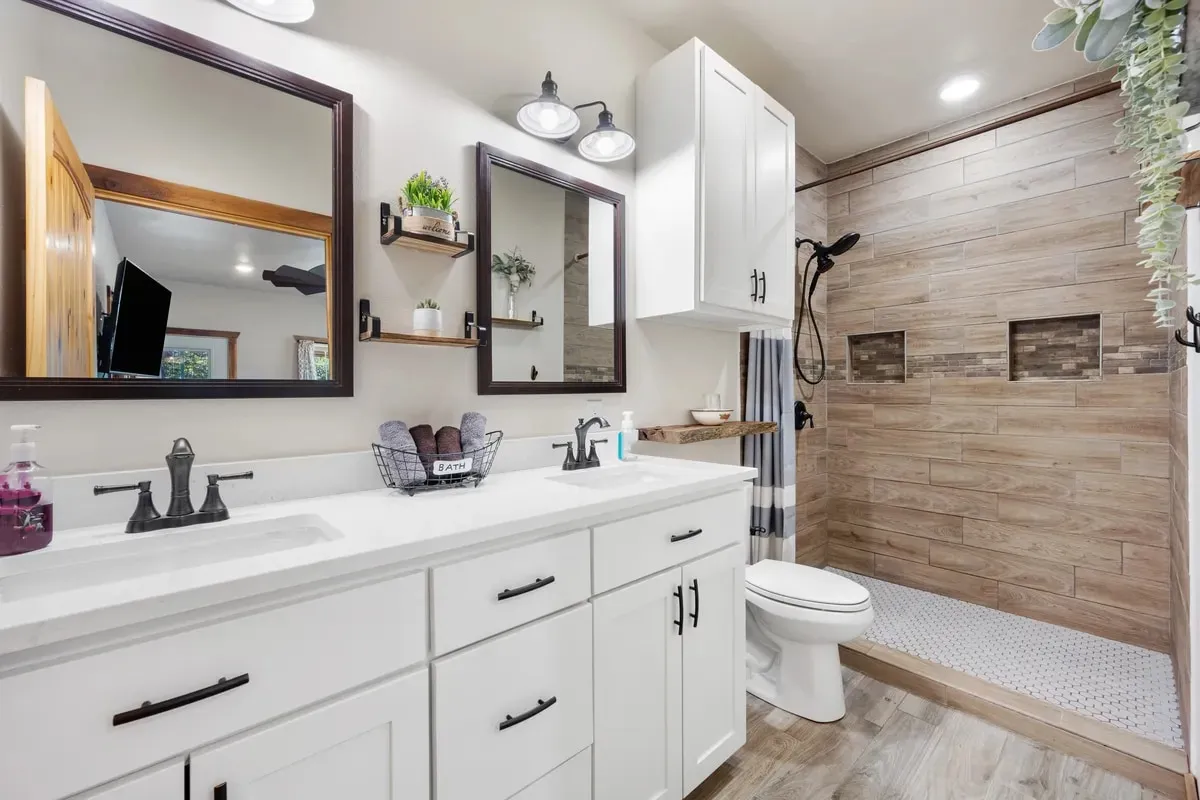 White vanity with black fixtures beside a walk-in shower tiled in wood-look plank