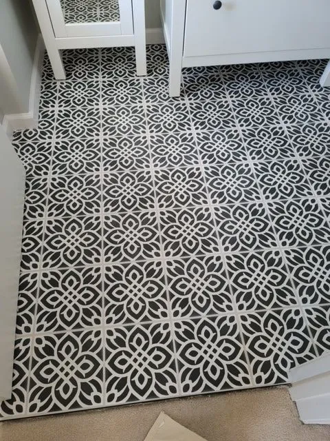 Black and white encaustic pattern tile laid across a bathroom floor