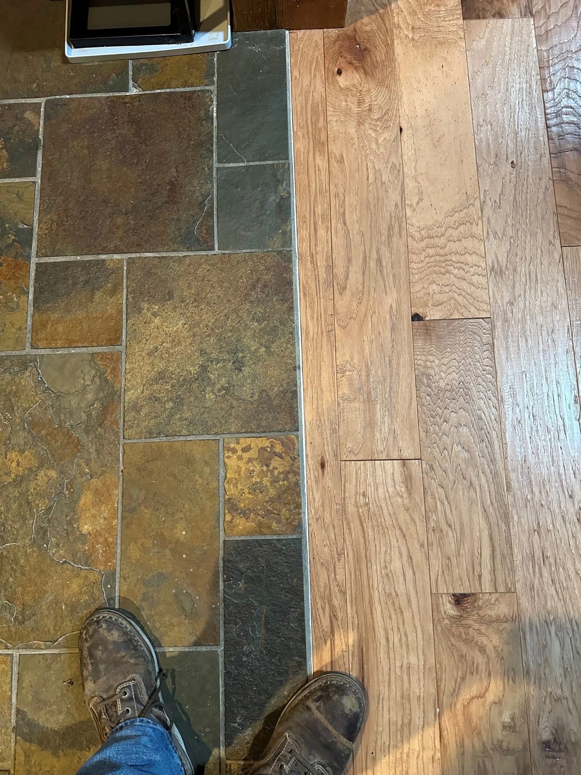 Slate and hardwood floors meeting along a straight seam, seen from above