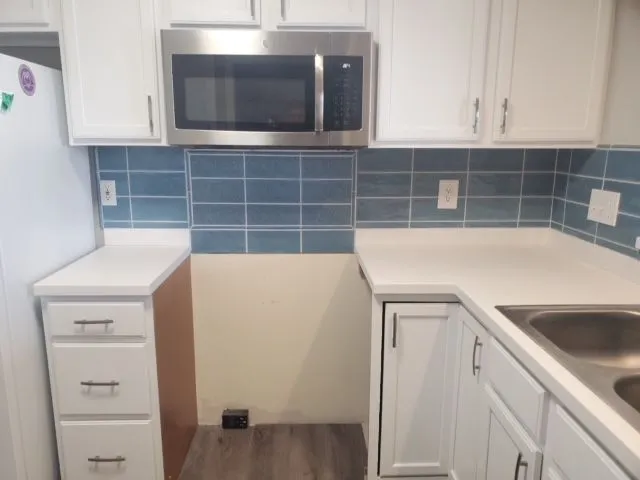 Blue subway tile backsplash above white cabinets