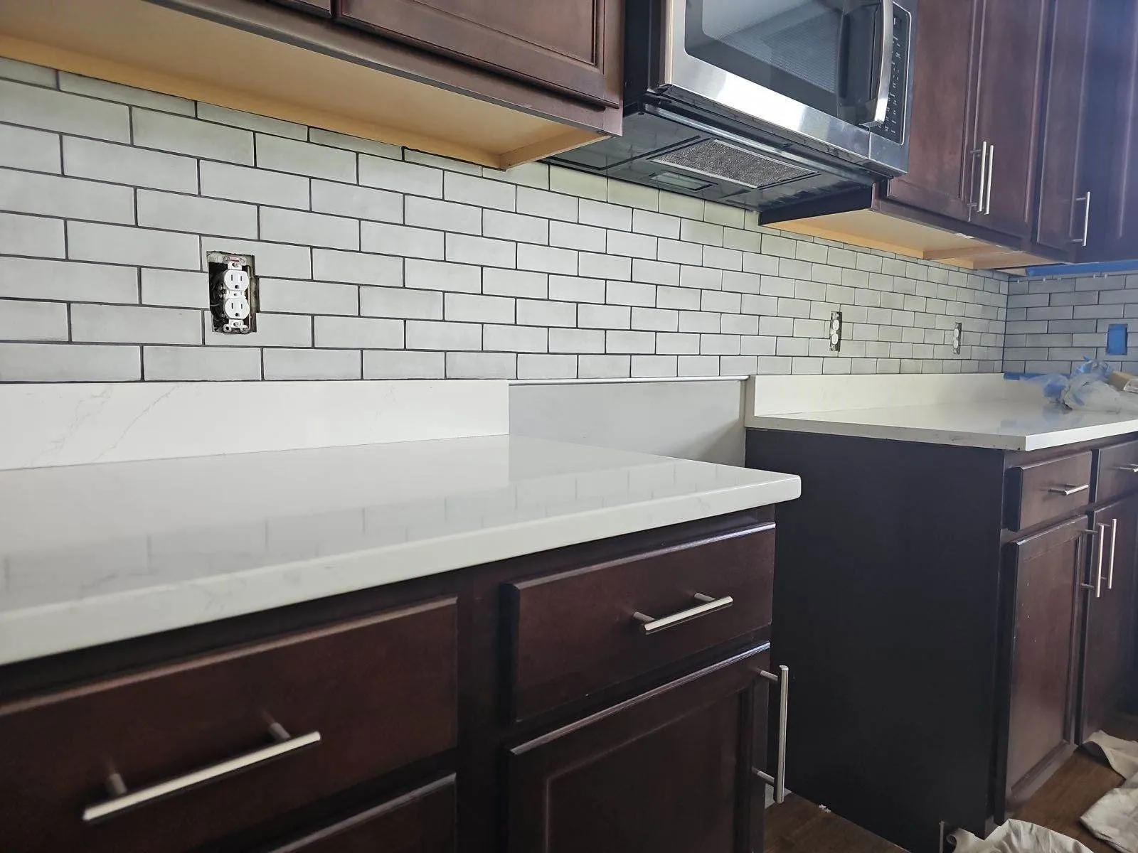 White subway tile backsplash above a quartz counter and dark cabinets
