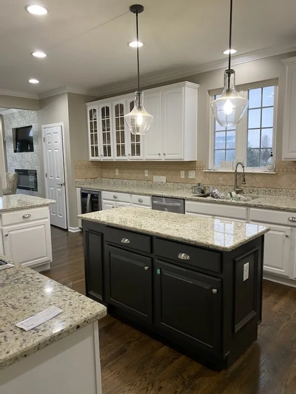 White kitchen with a black island and granite counters