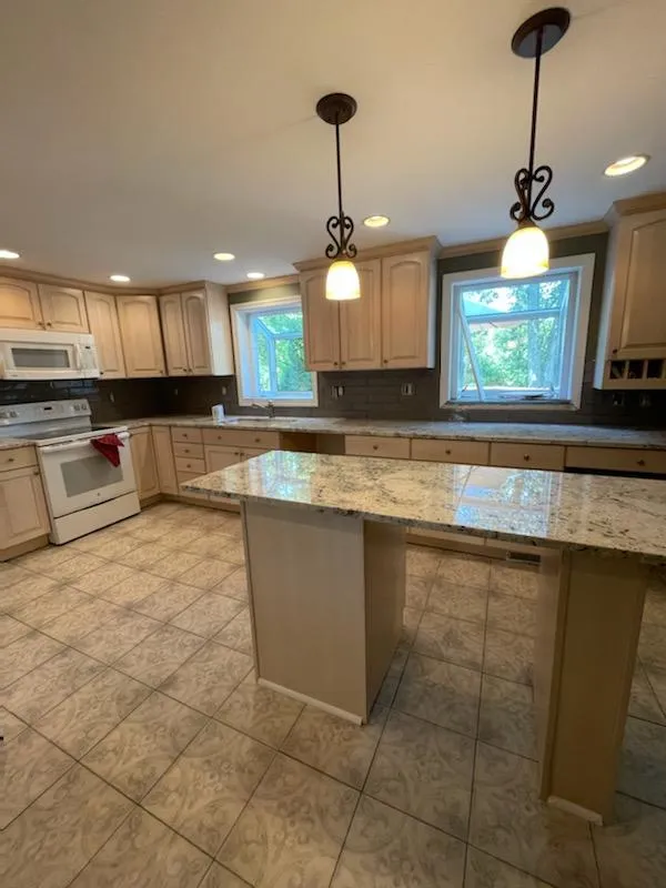 White kitchen cabinets with granite counters and a tile floor