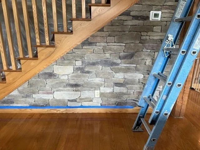 Dry-stacked stone veneer wall following the underside of a staircase